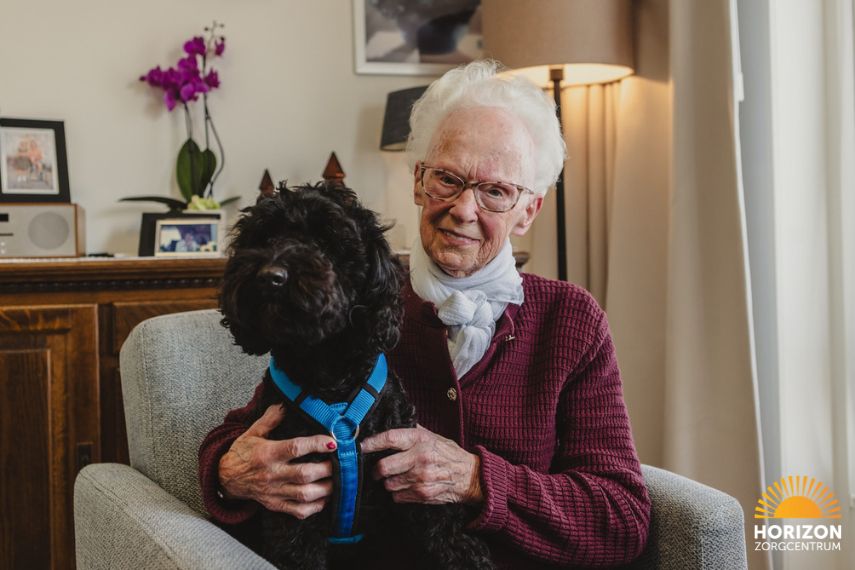 Bewoner knuffelt met hond op kleinschalig wonen